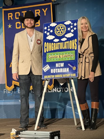 New Arlington Sunrise Rotarian stands beside a congratulations sign with his sponsor