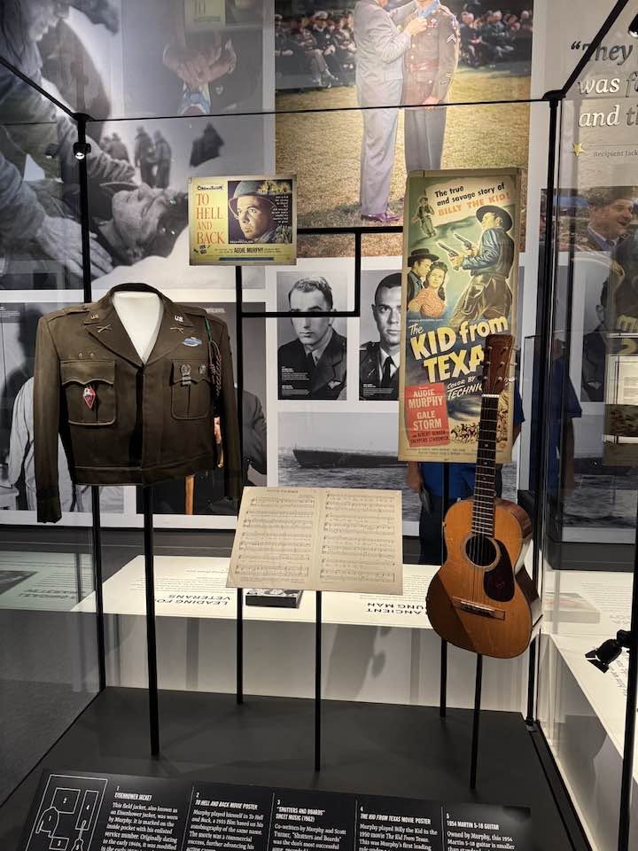 Museum display with a military jacket and guitar seen on an Arlington Sunrise Rotary outing